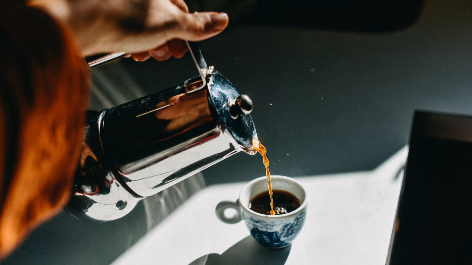 en kopp kaffe fylles fra en fransk presse i rustfritt stål