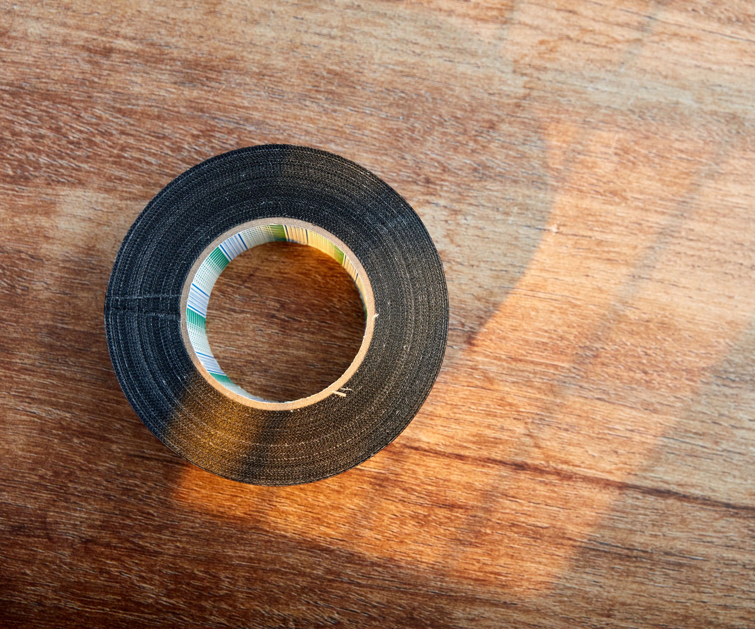 En rull med svart tape på en treoverflate