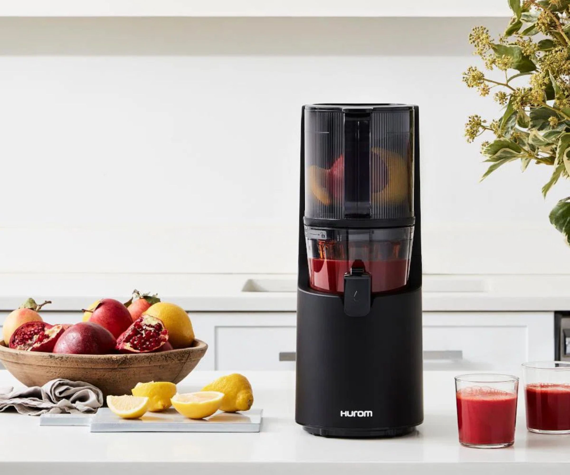 En svart Huron juicer på en benkeplate med frukt til venstre for den