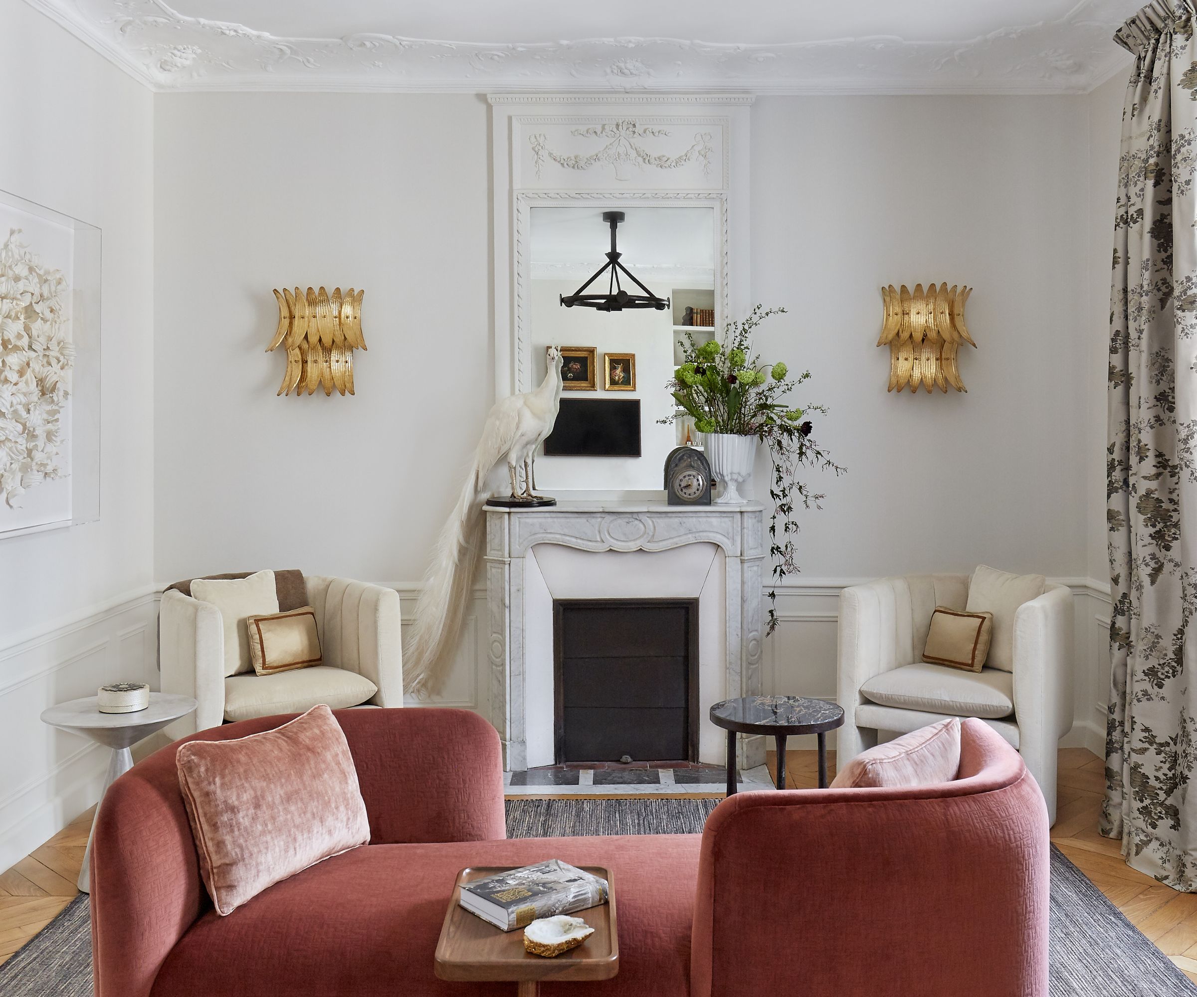 stue med rosa tete ved tete sofa og to hvite lenestoler ved peisen