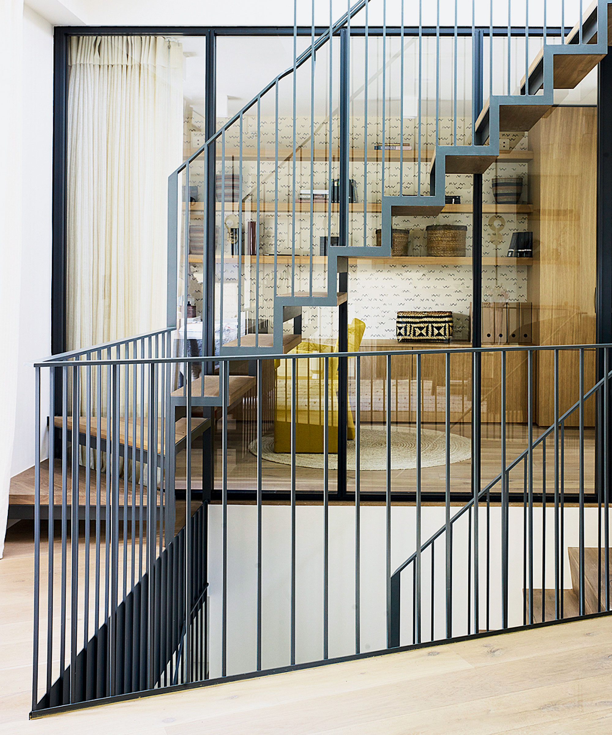 Moderne hjem med elegant tre- og ståltrapp, grafisk design, ser gjennom glasspaneler til salongområdet