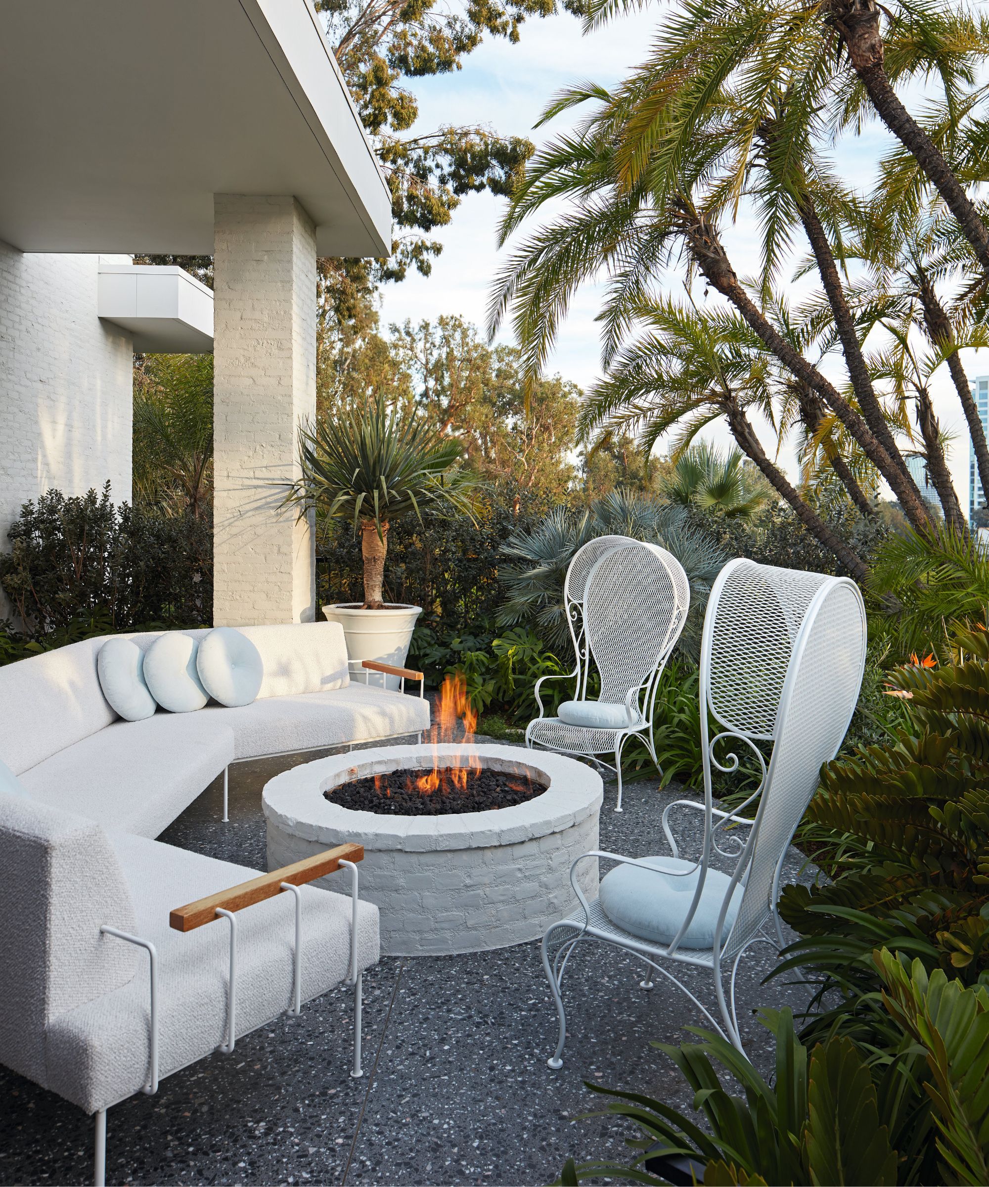 utendørs terrasse med sofa bål og hvite jernstoler