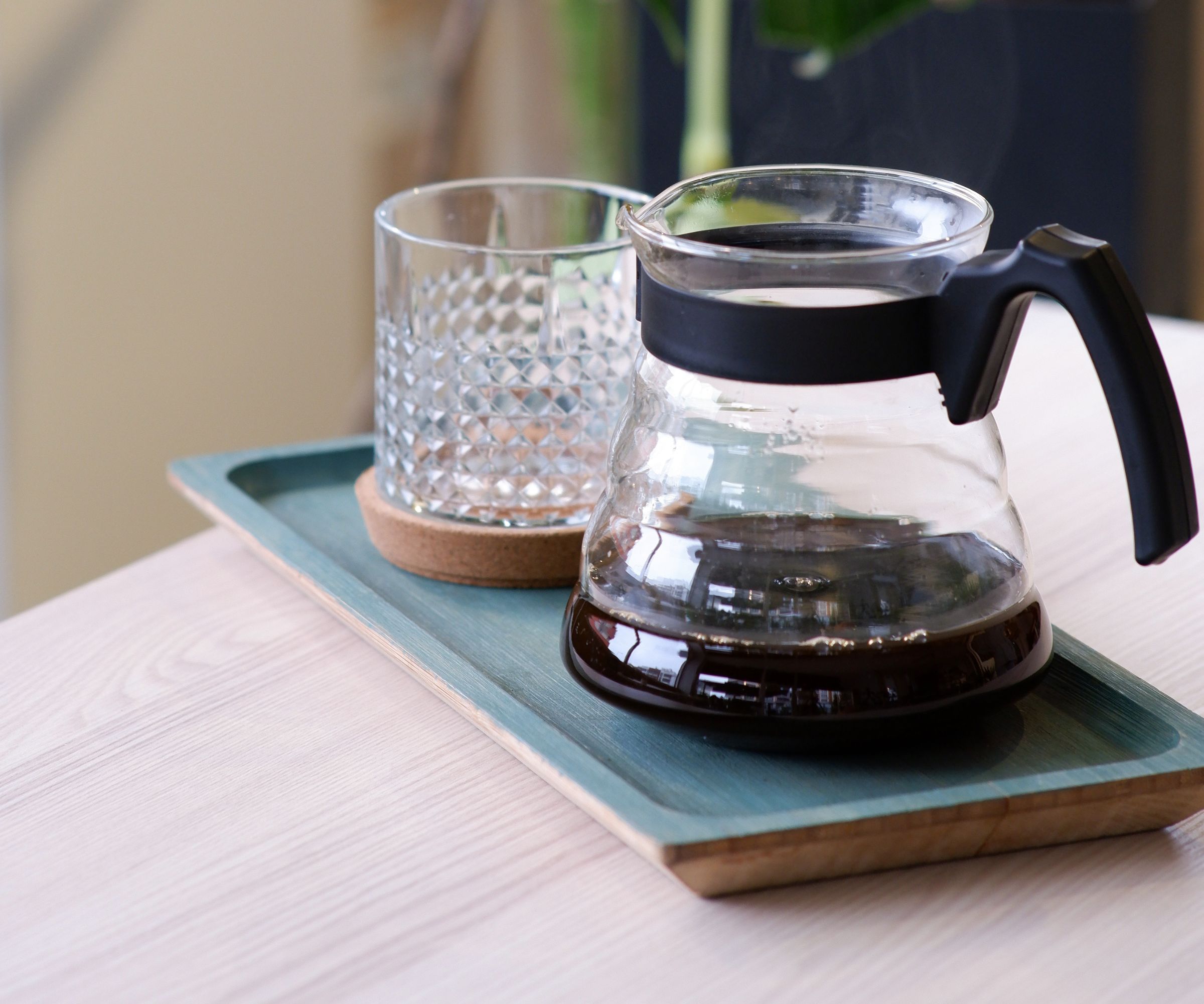 En glass drypp kaffetrakter karaffel på et brett med et kaffeglass