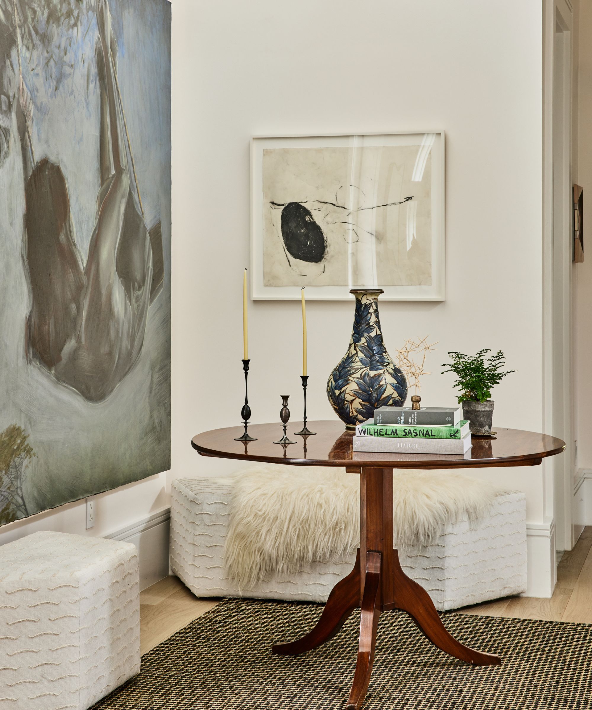 entryway med hvite vegger store kunstverk antikke pidestall bord og kube benker