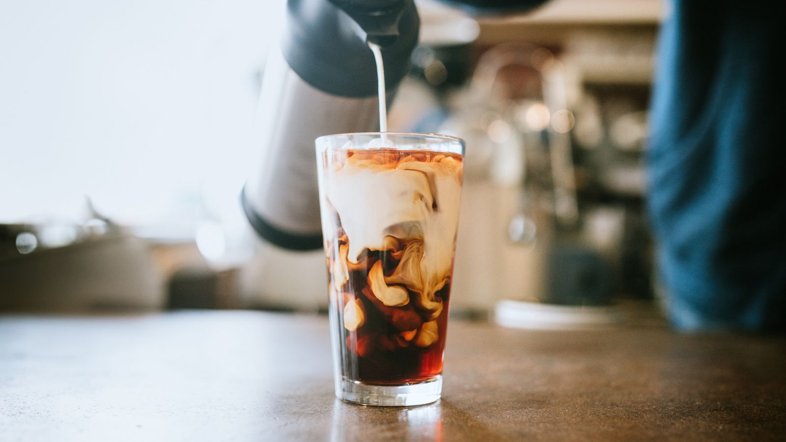 Melk som helles i et glass kaffe, gir en marmorert effekt