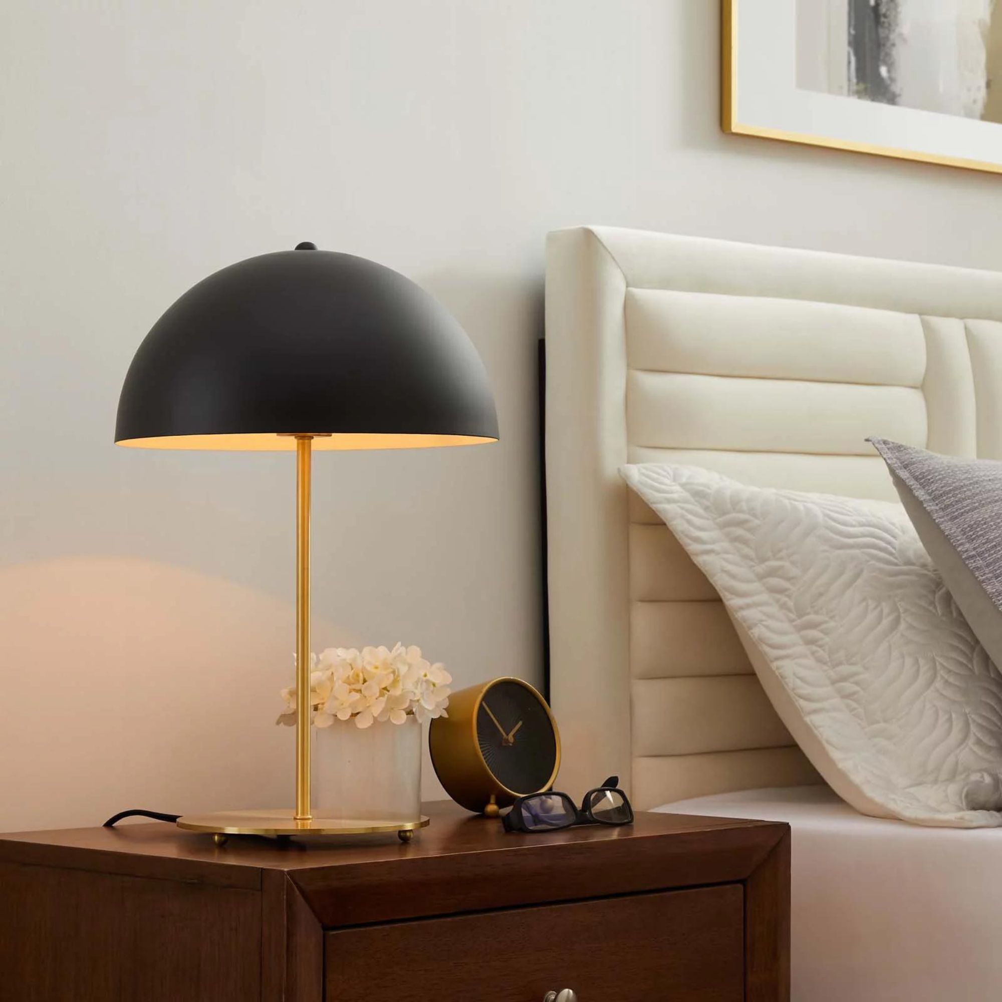 En moderne bordlampe i gull og sort fra midten av århundret på et nattbord