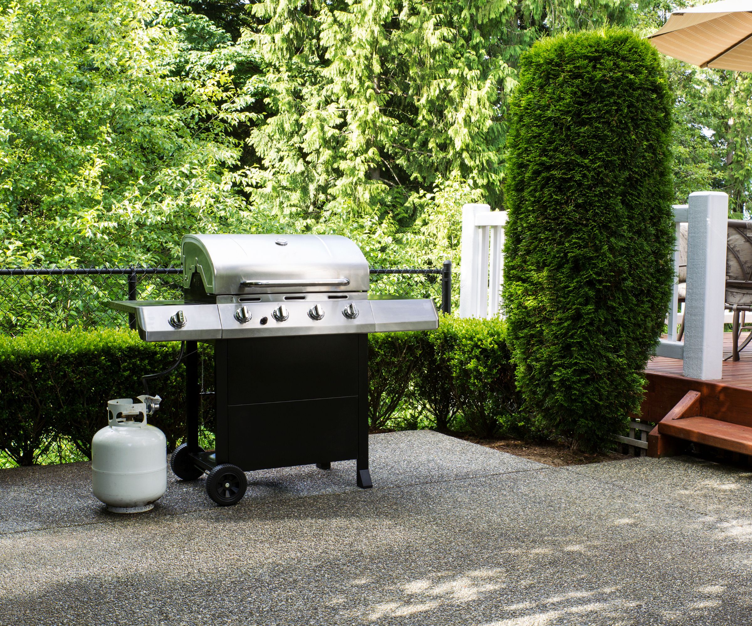 En hvit propantank ved siden av en gassgrill