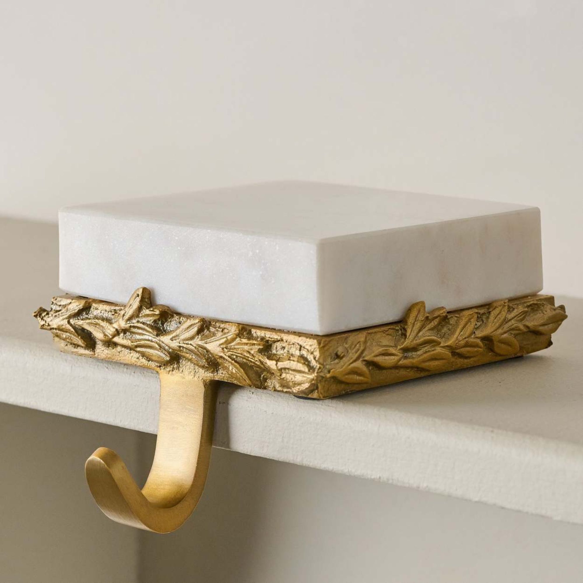 Marmor og forgylt strømpeholder på en hvit mantel.