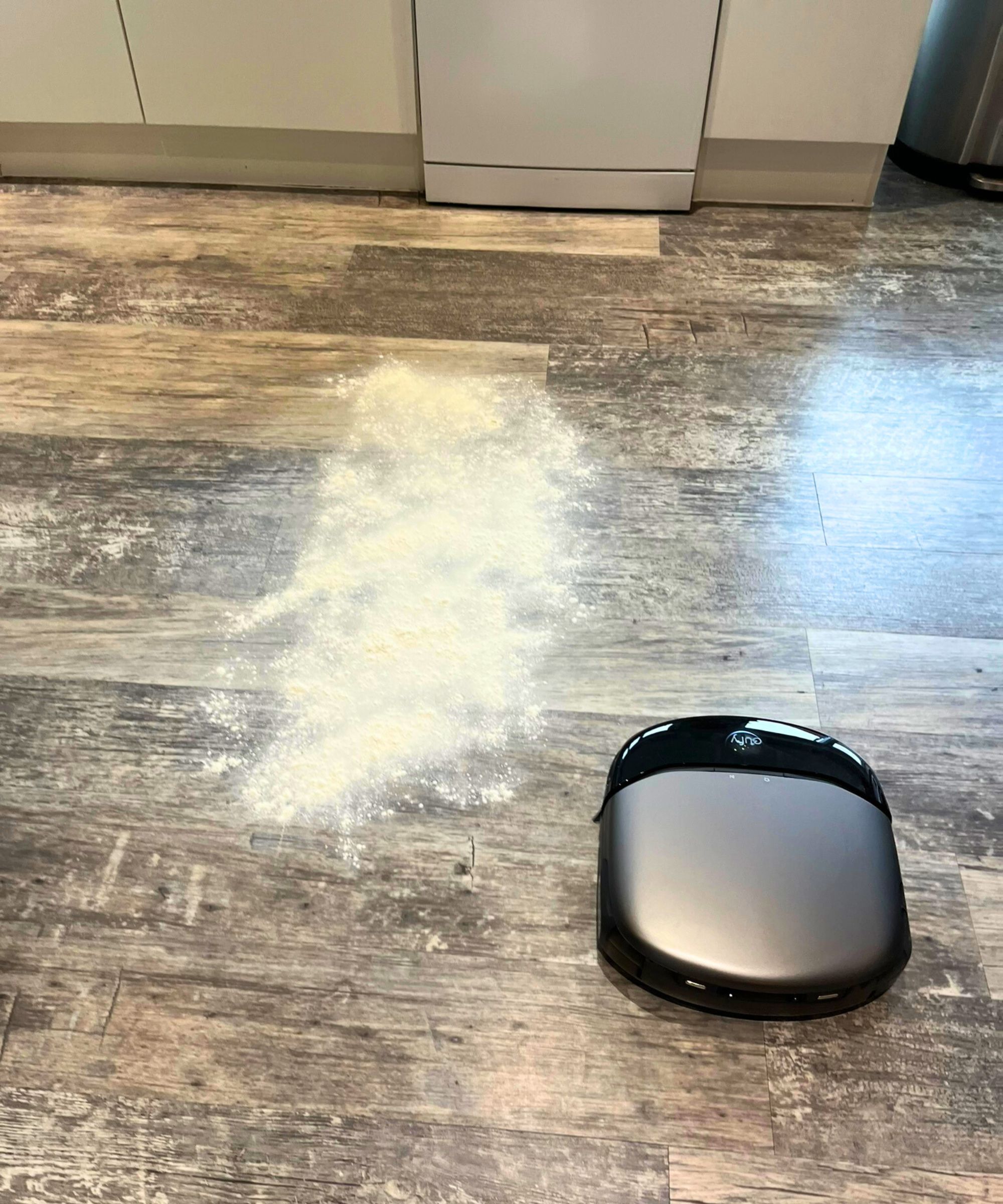 Eufy Omni S1 Pro Robot Vacuum på tregulv med en kopp mel spredt over gulvet, i Punteha Van Terheydens hjem.