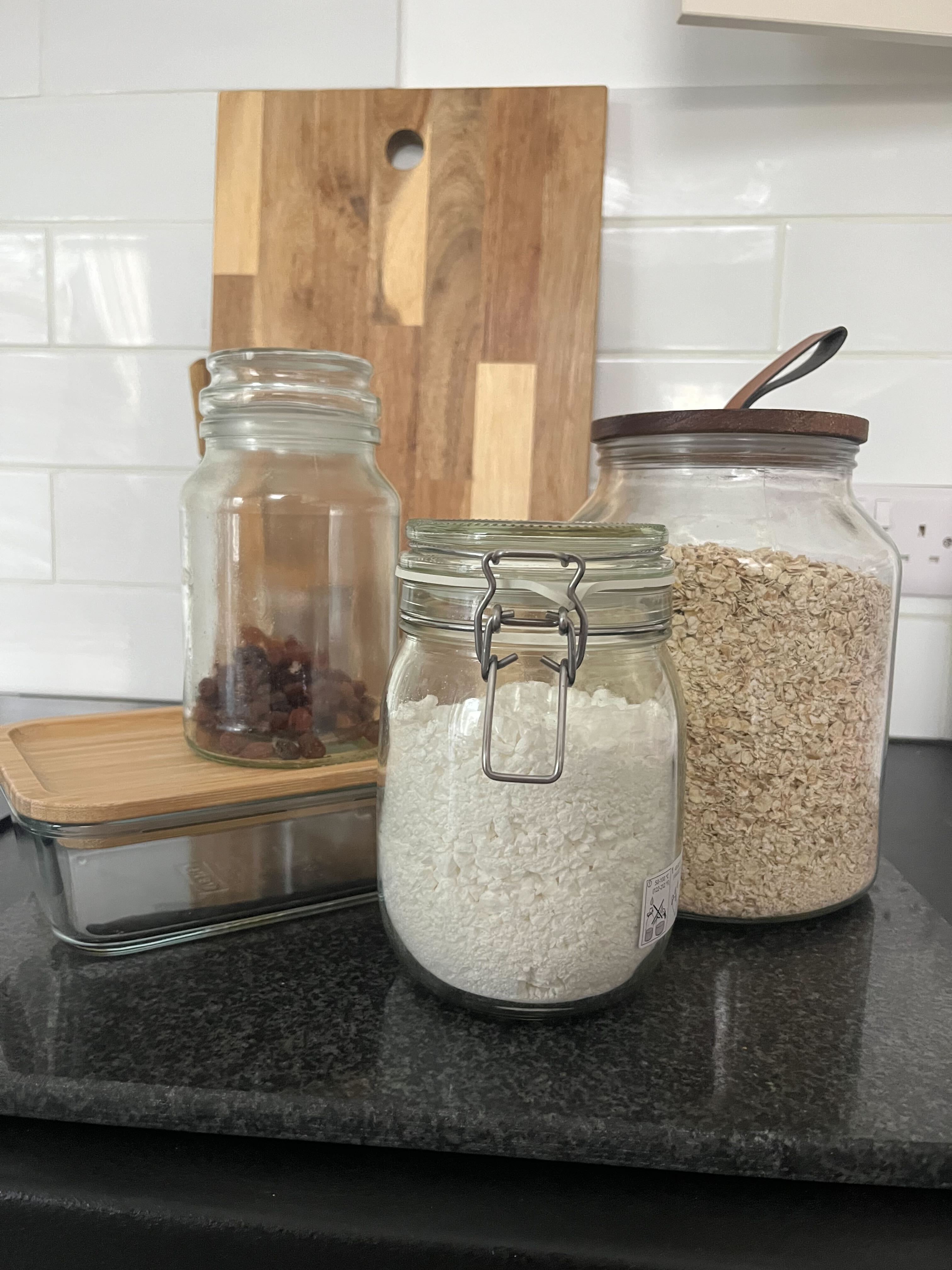 Glassmatoppbevaringskrukker fylt med sukker, havre og tørket frukt