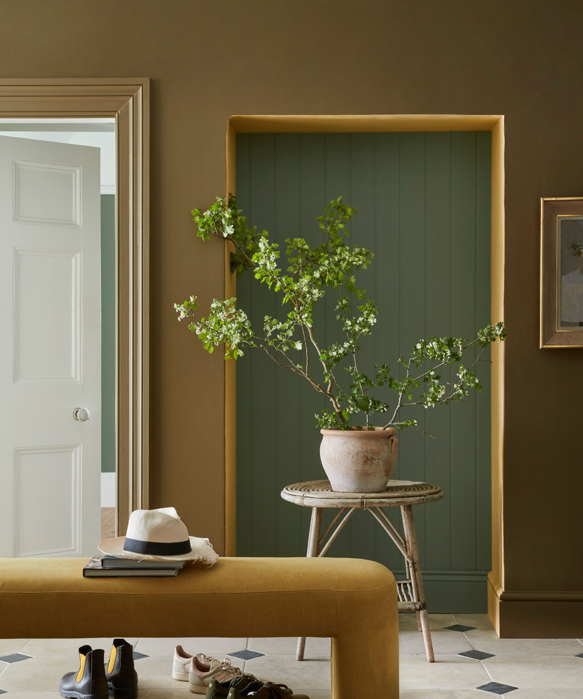 entré med brungrønne vegger, grønn dør og plante på sidebord