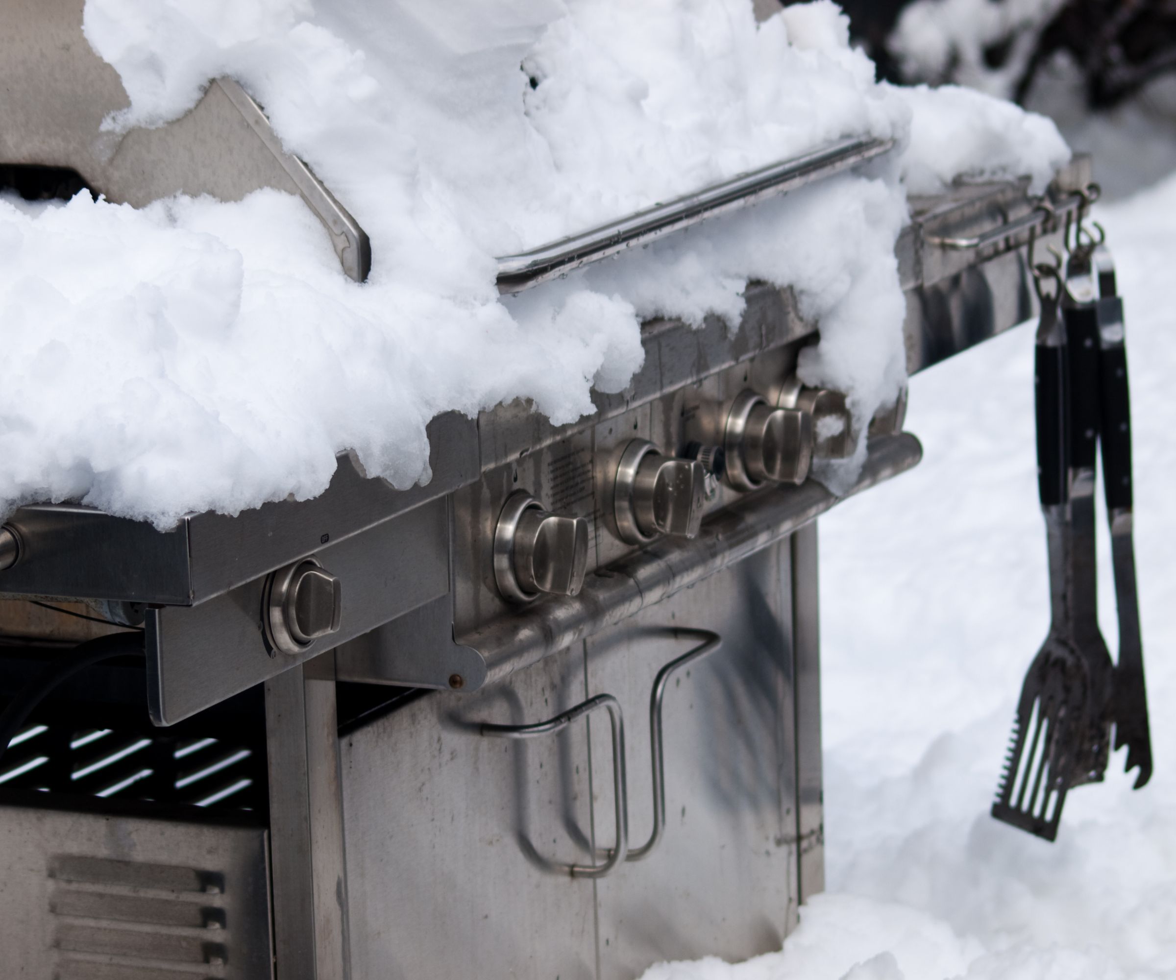 Nærbilde på en gassgrill dekket av snø