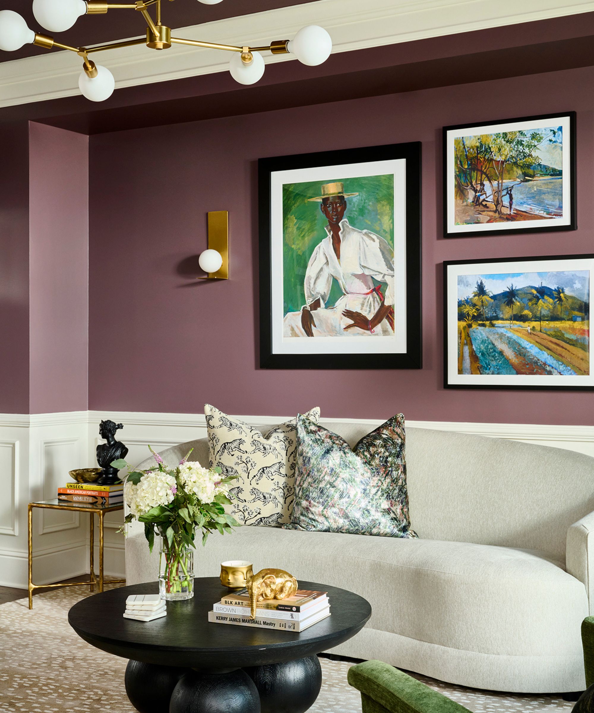 stue med lilla vegger, krembuet moderne sofa, svart rundt salongbord, fargerike kunstverk på veggene
