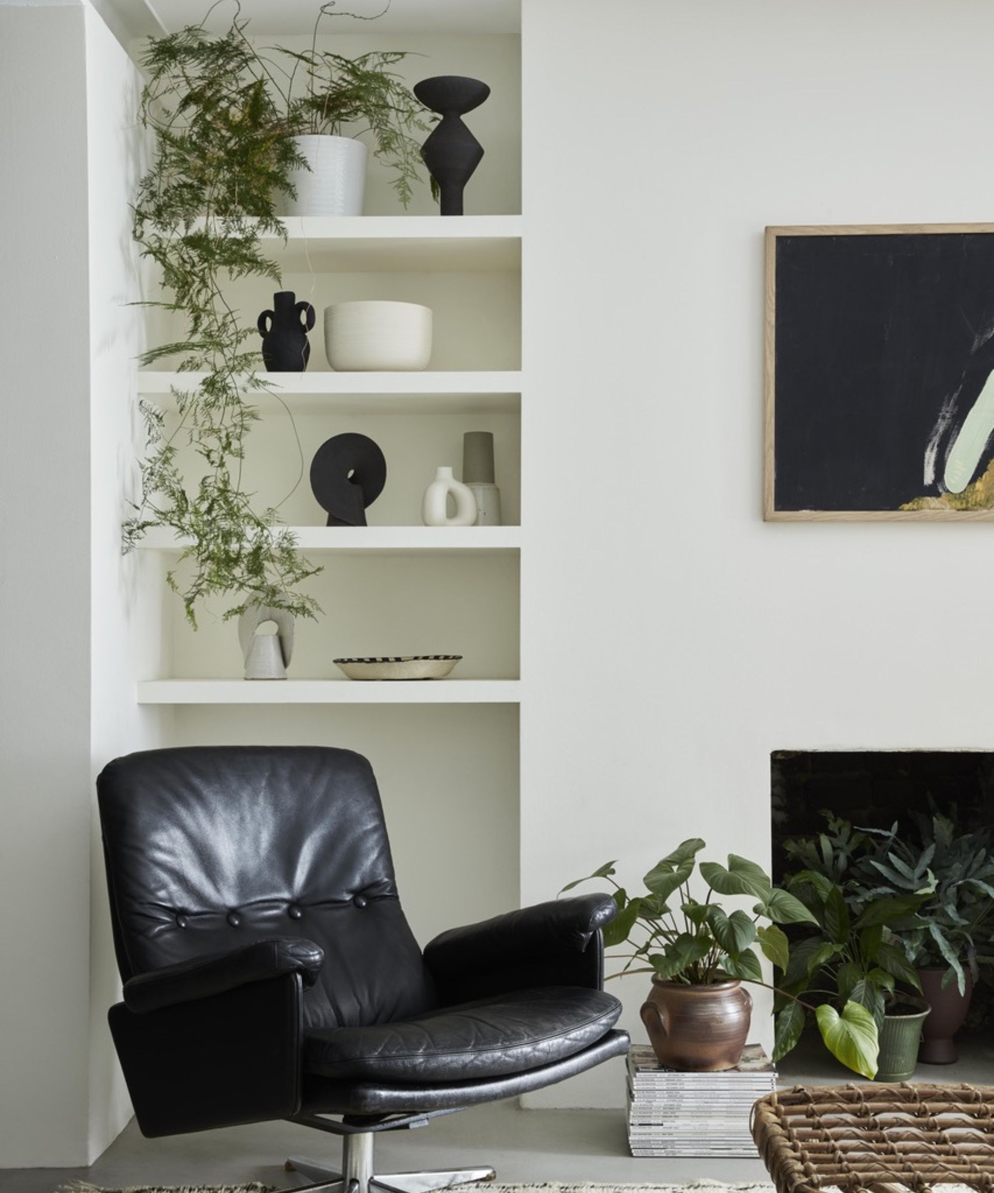 hjørne av stuen med hvite vegger med hyller, svingbar stolstol, mange planter