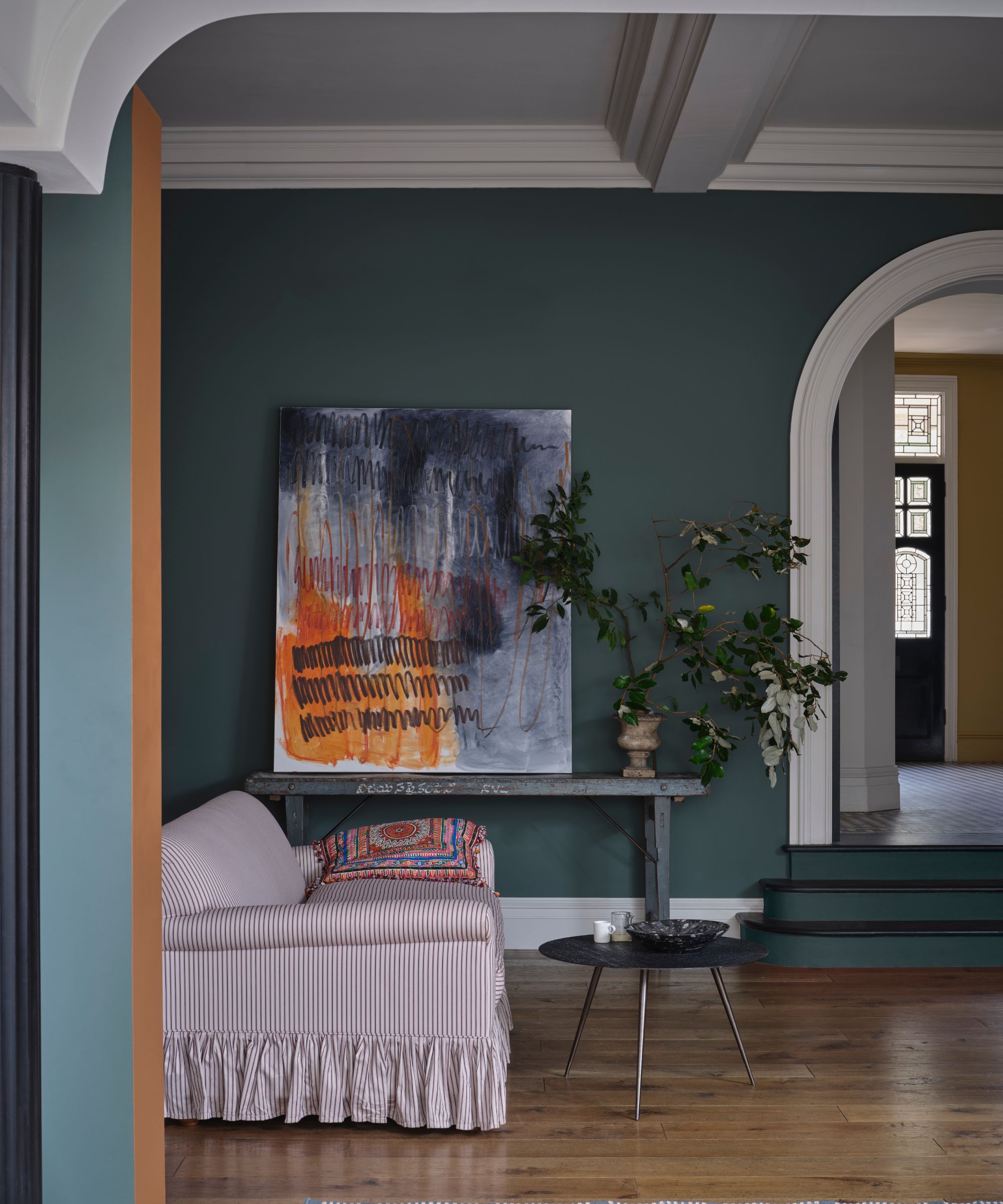 boareal med mørkegrønne vegger, hvit trim og tak, dristig kunstverk, lysrosa stripete sofa og tregulv