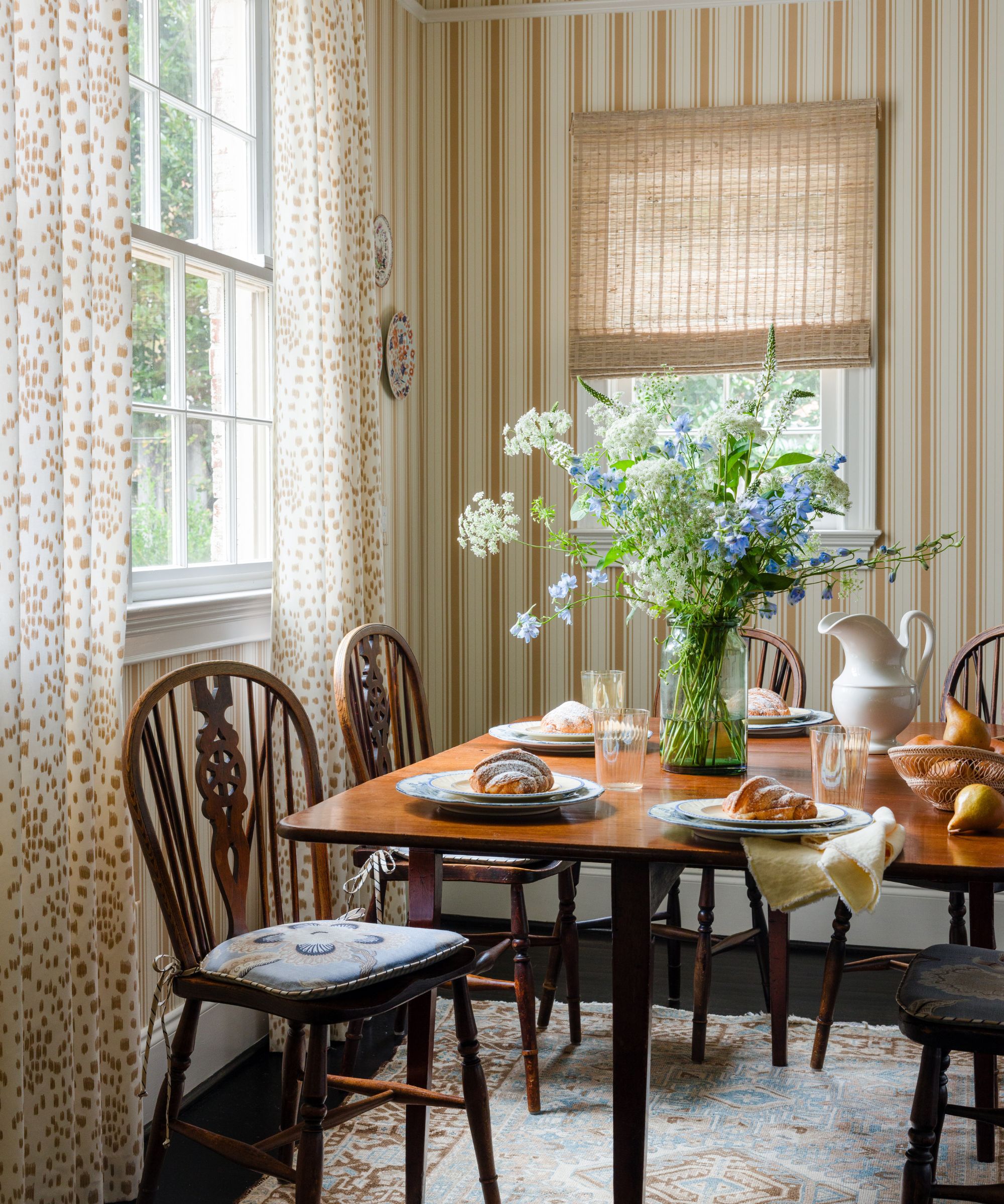 Frokostkrok med stripete vegger, trebord og spisestoler med vårblomster og frokostmat