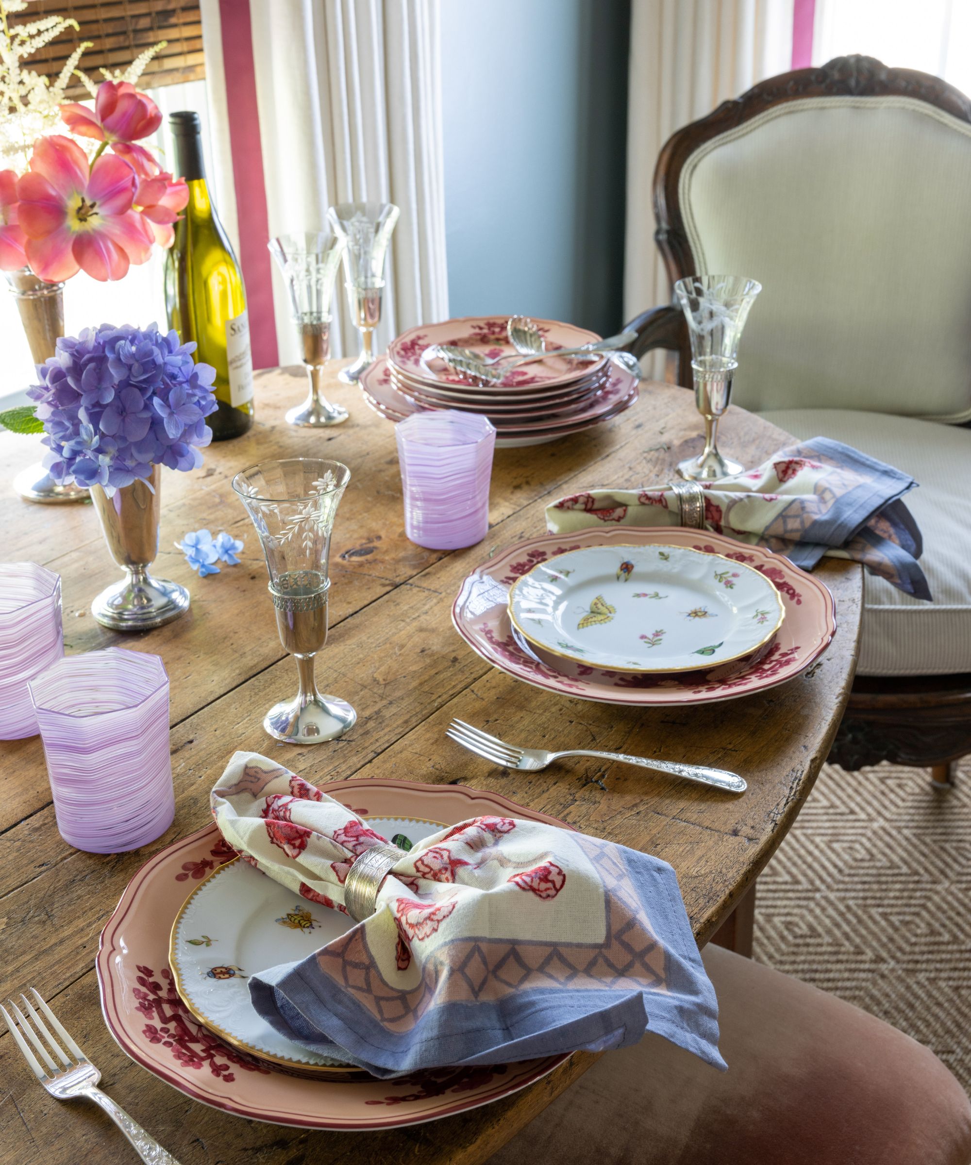 Trebord med rosa Kina -tallerkener, mønstrede servietter, rosa glassvarer og champagnefløyter