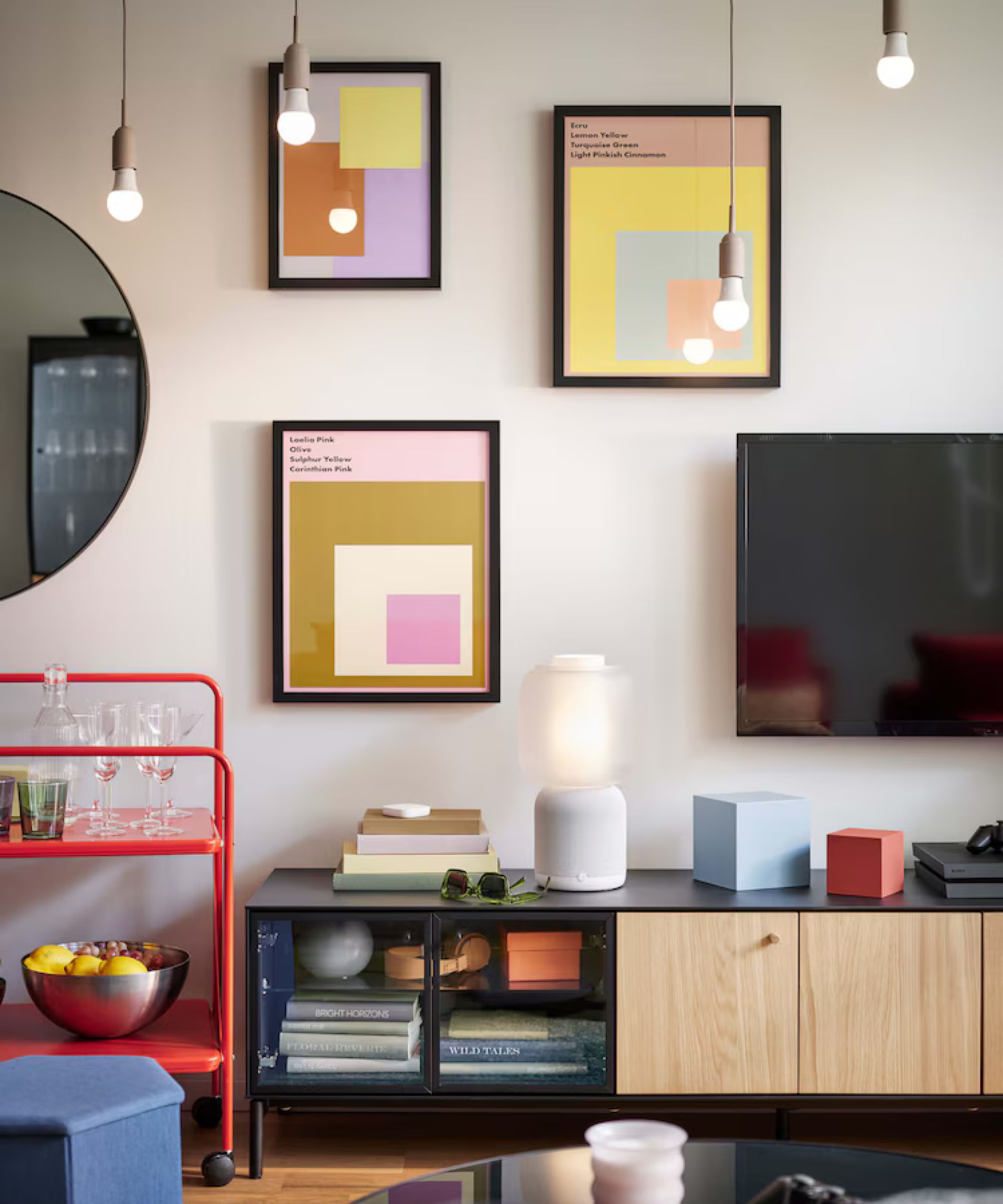 Ikea stue med utskrifter på veggen og lavt TV -skap i svart og tre med neon oransje bar -vogn