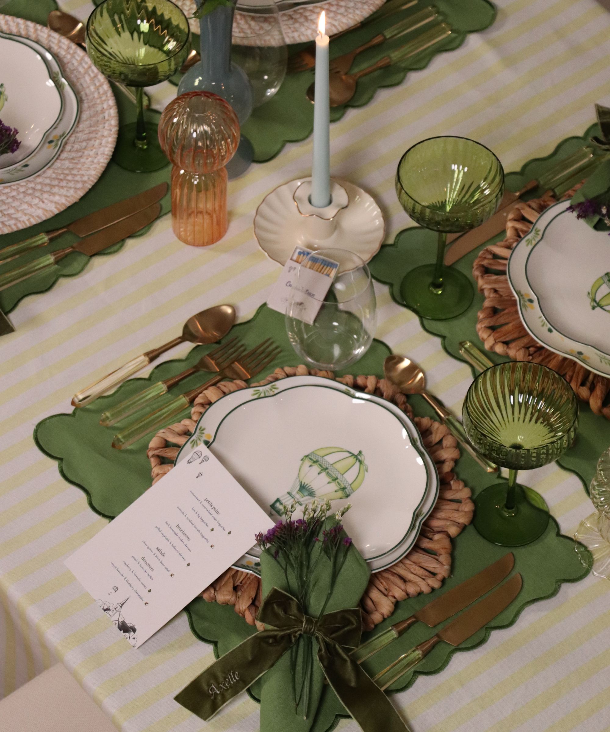 Grønn vårbord med kamskjellede placemats, stripete duk, rotting placemats og porselen plater