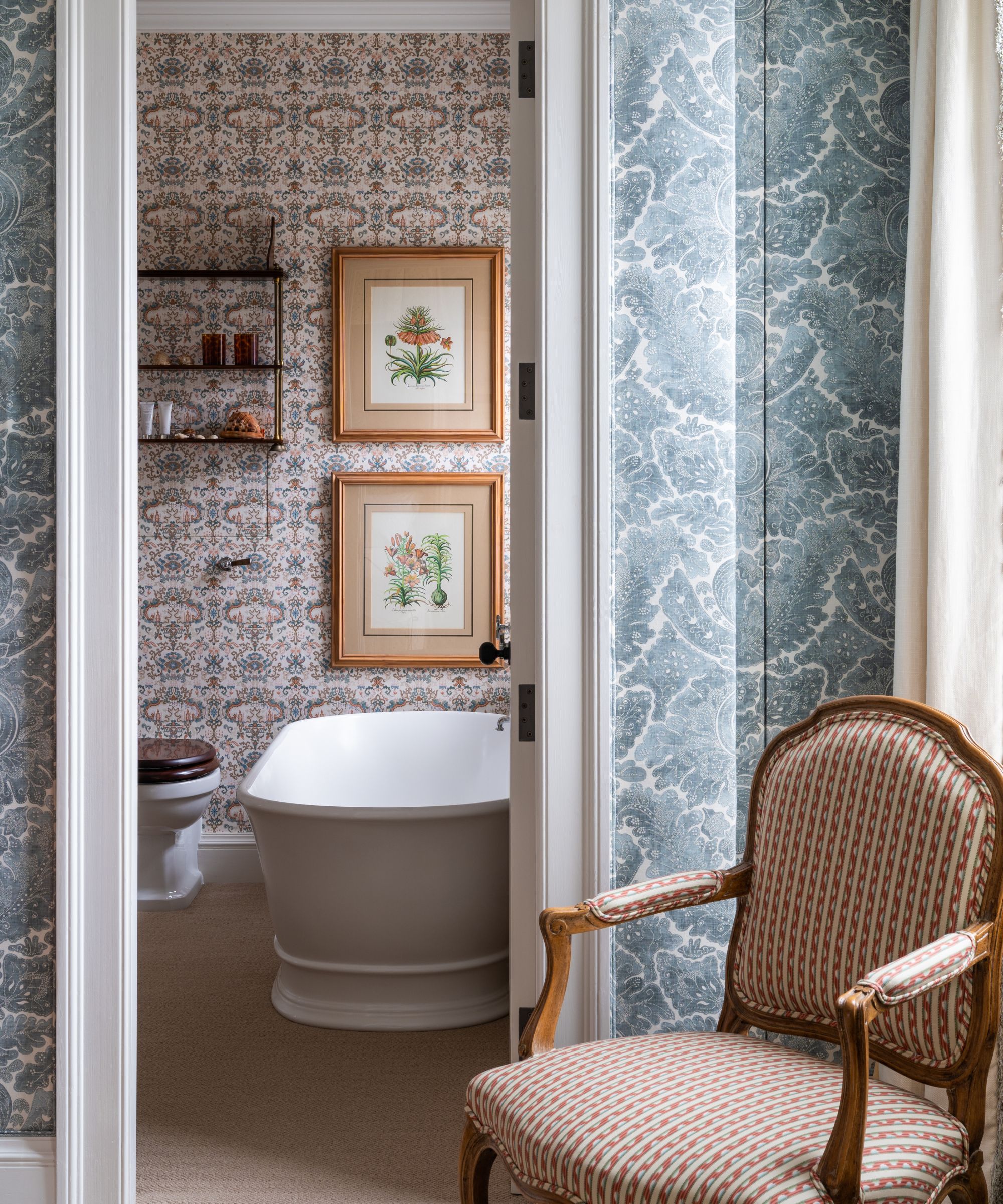 Bakgrunnsbad med vintage blomstertrykk, badekar og hylle og vintage polstret stol
