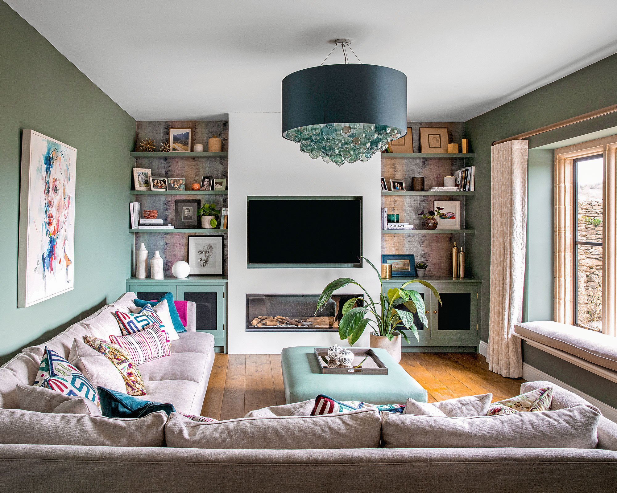 Grønn stue med L-formet sofa og veggmontert TV
