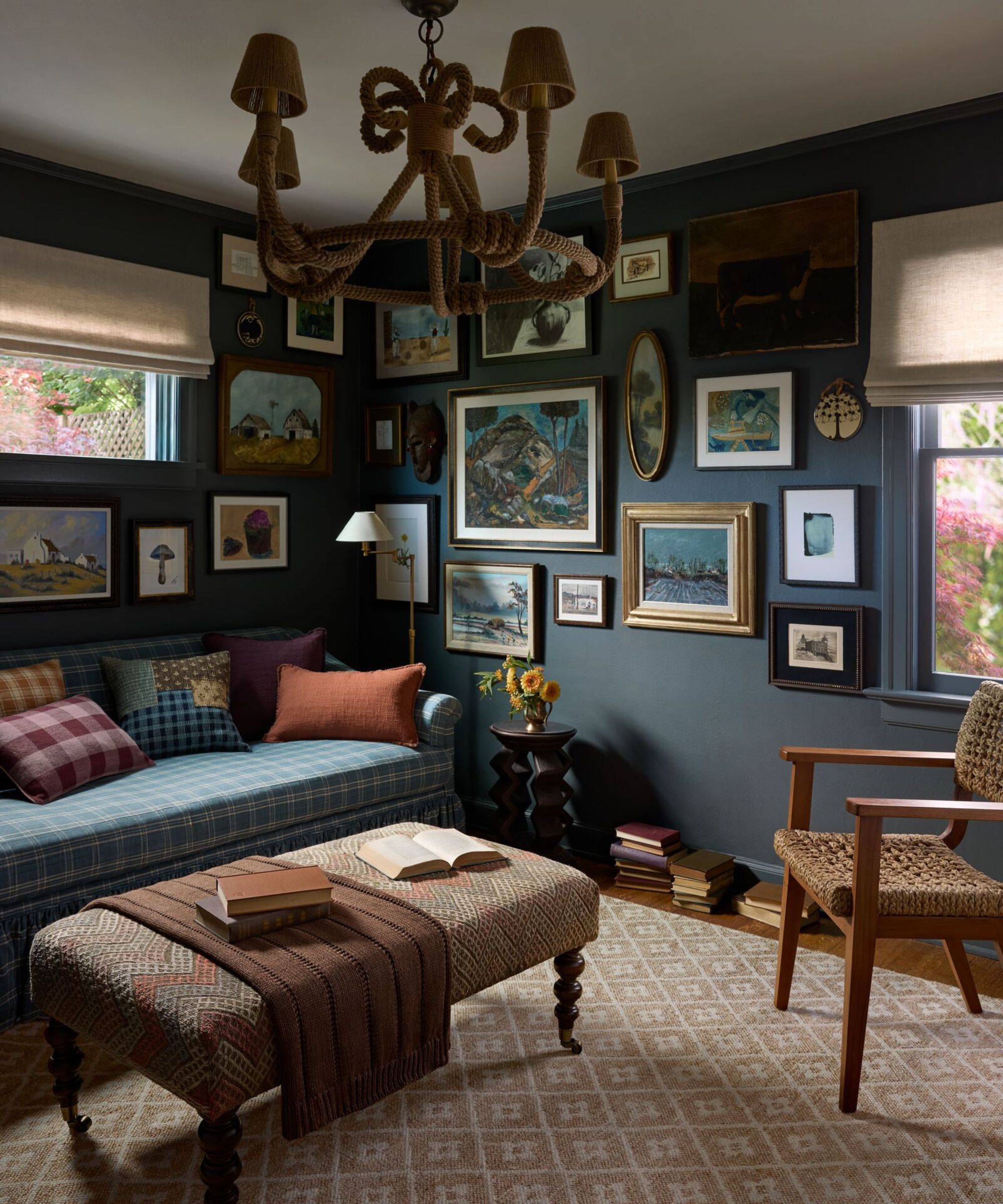 Navy Blue Snug Familierom med en gallerivegg og en blå pledd sofa med mønstrede puter og et nøytralt vevd teppe