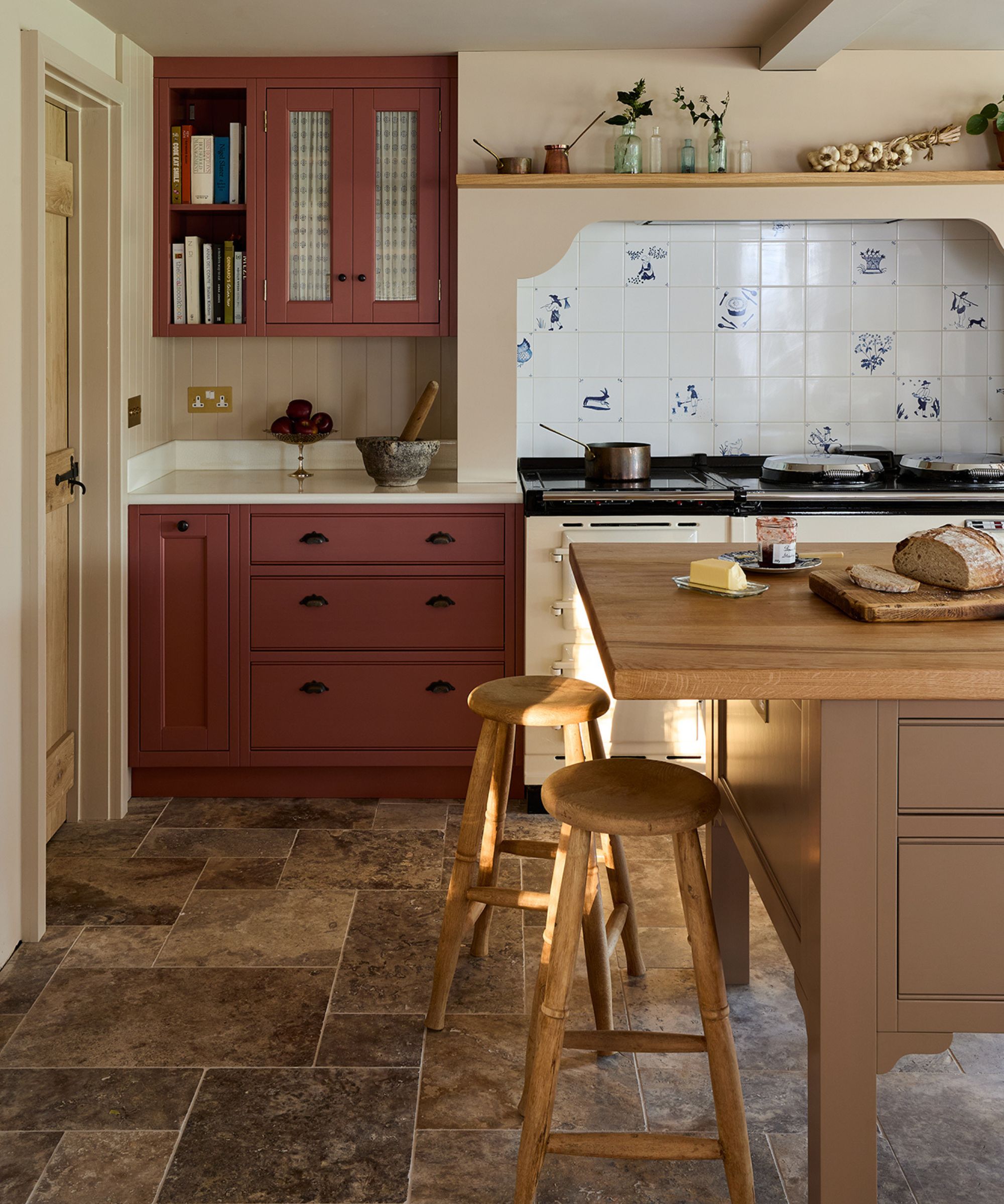 Country Farmhouse Kitchen med en vintage stil med to tone skap rosa og beige, en stor treøy og en enorm komfyr med Delft -fliser til baksiden