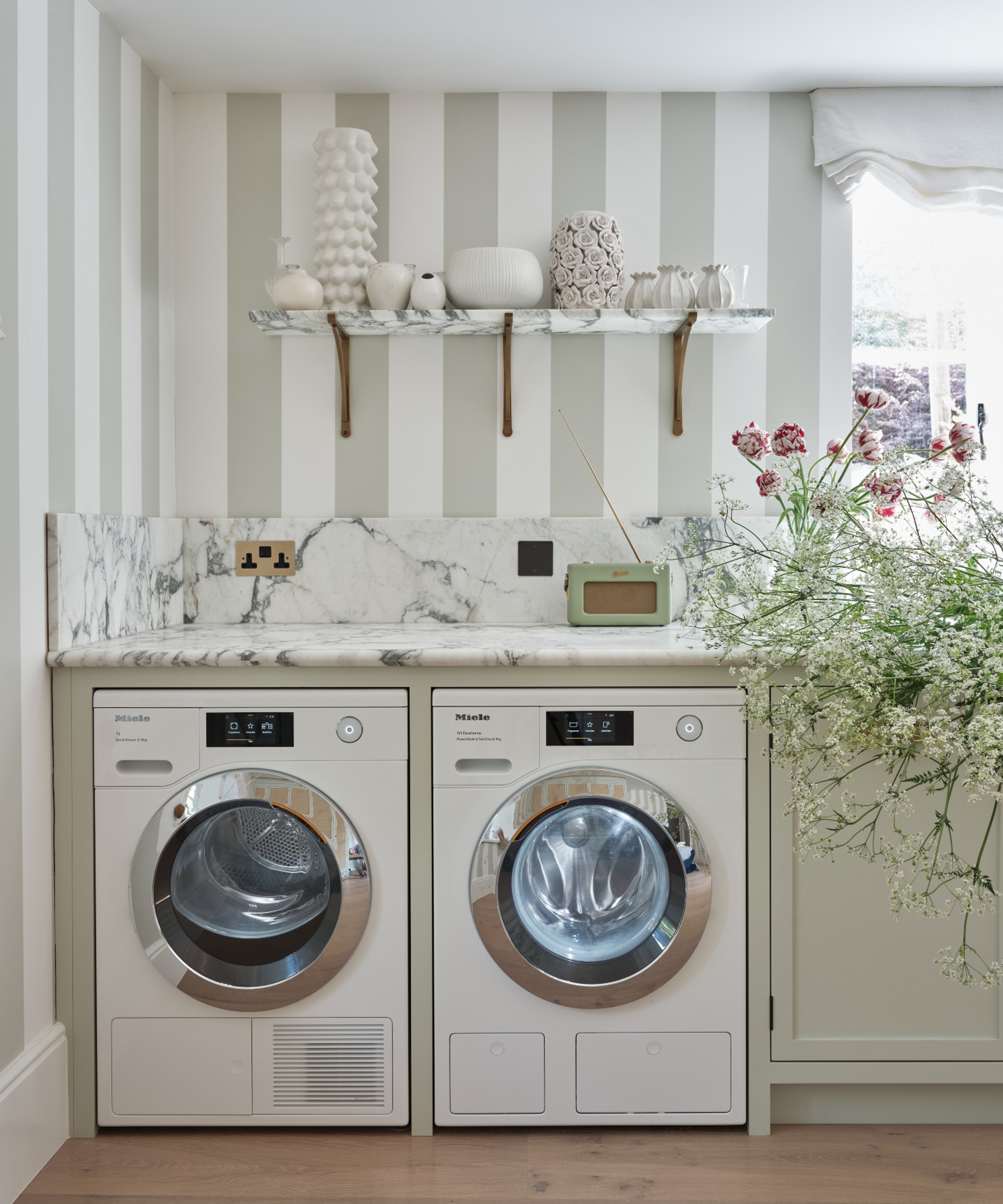 Miele vaskemaskin i et elegant våningshusstilvaskrom med stripete tapet og blomster i vasken