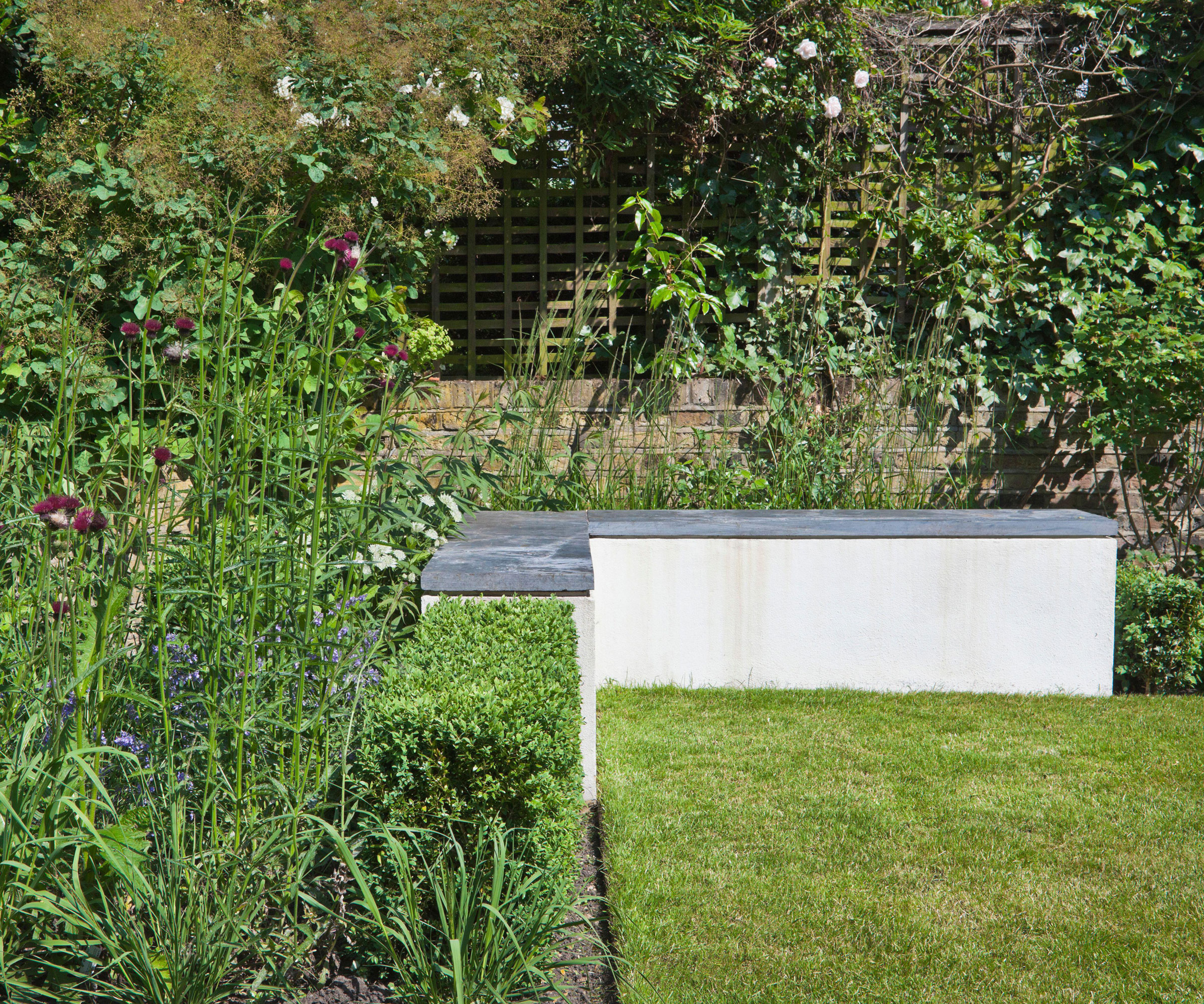 Betong L-formet hagebenk med plen og blomsterbed