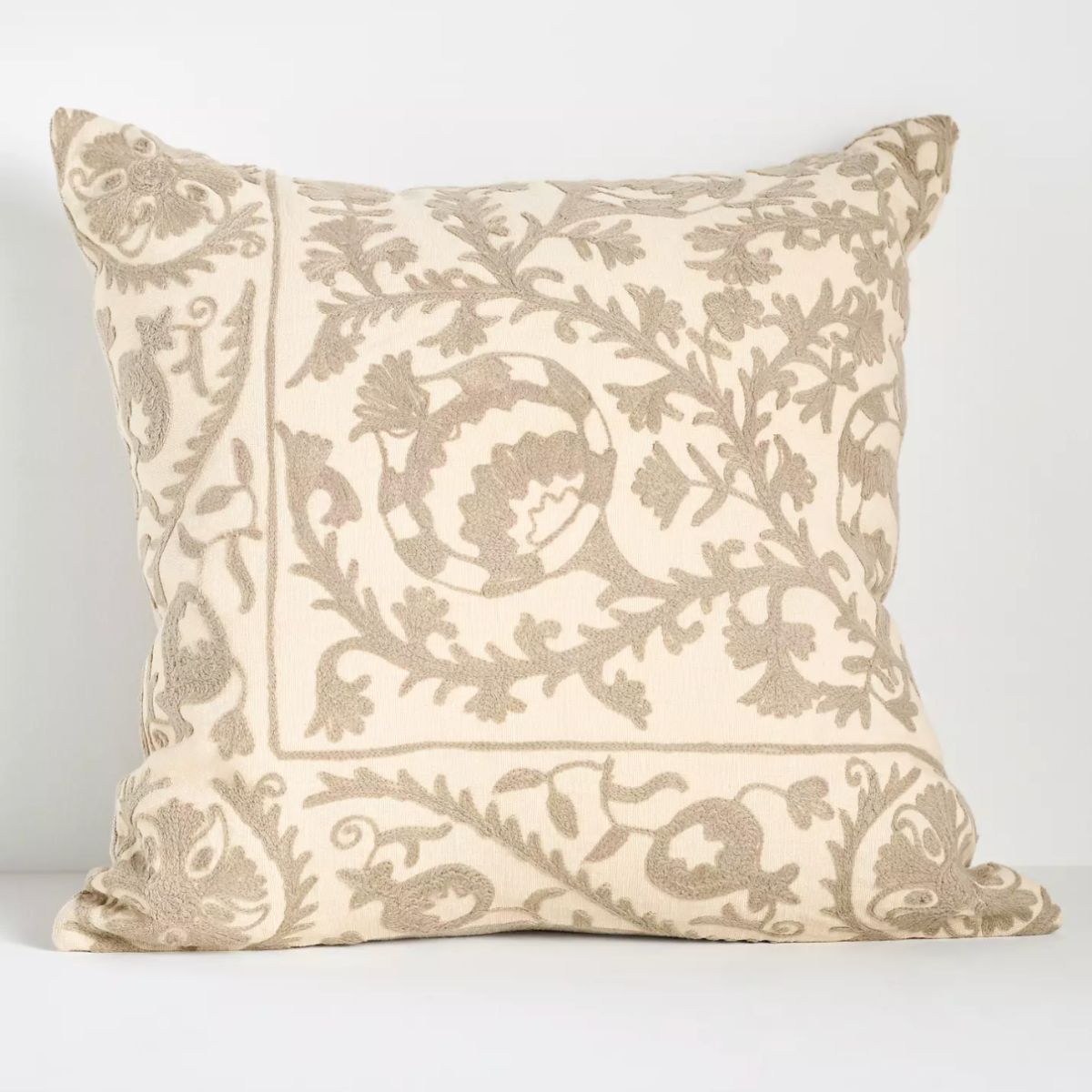 En nøytral pute med nøytral brodert blomsterdesign