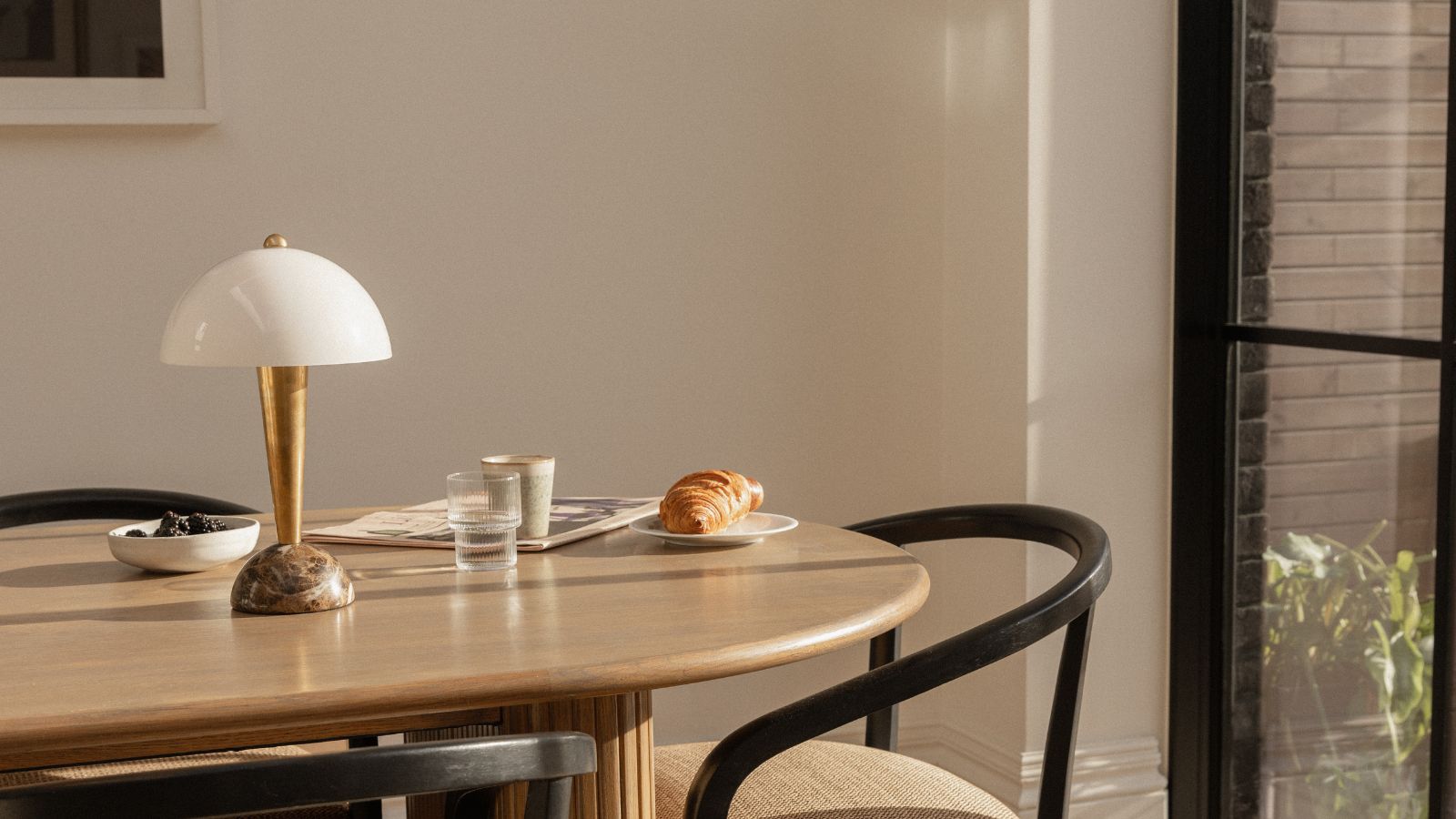 wooden kitchen table with gold marble and white lamp and black chairs