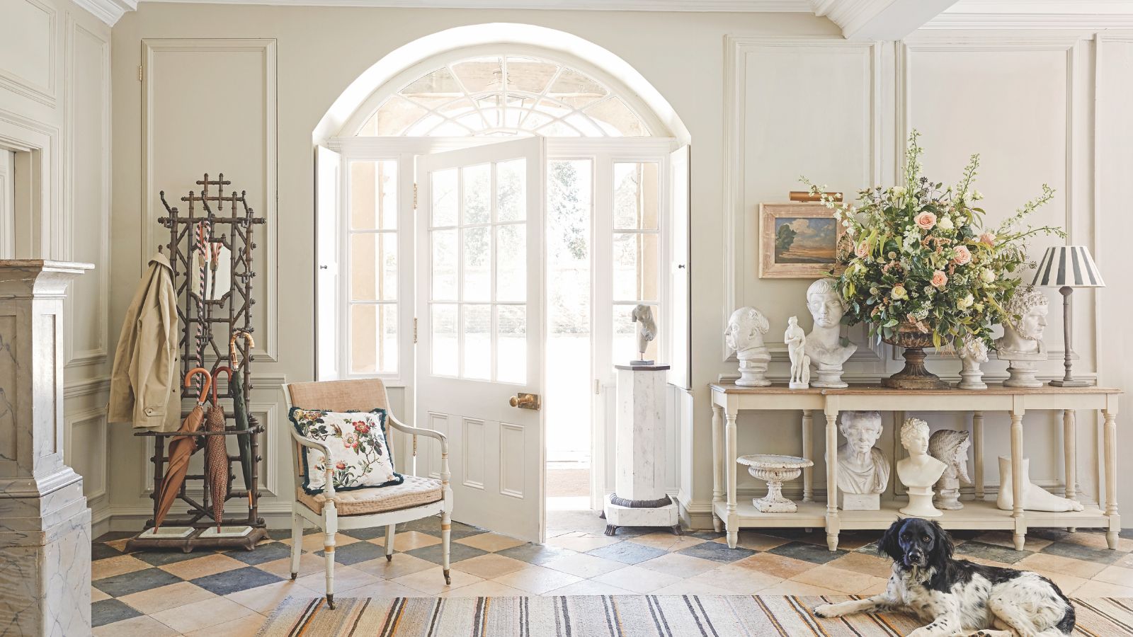 A traditional entryway painted white with a collection of patinated antique and vintage items displayed