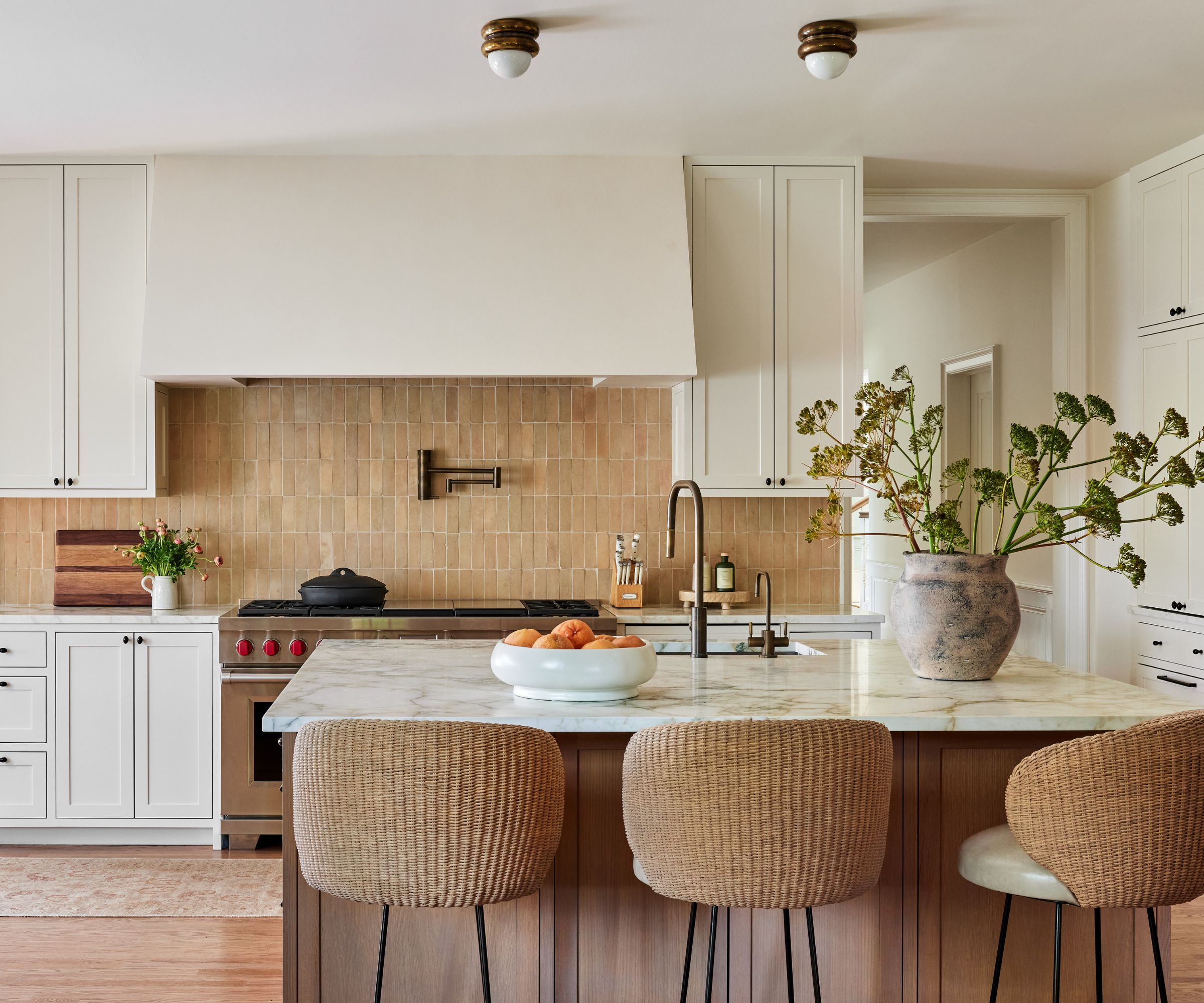 Kjøkken med brune zeillage -fliser, Marble Island, Rattan Bar Stools og rustikk vase med stilker