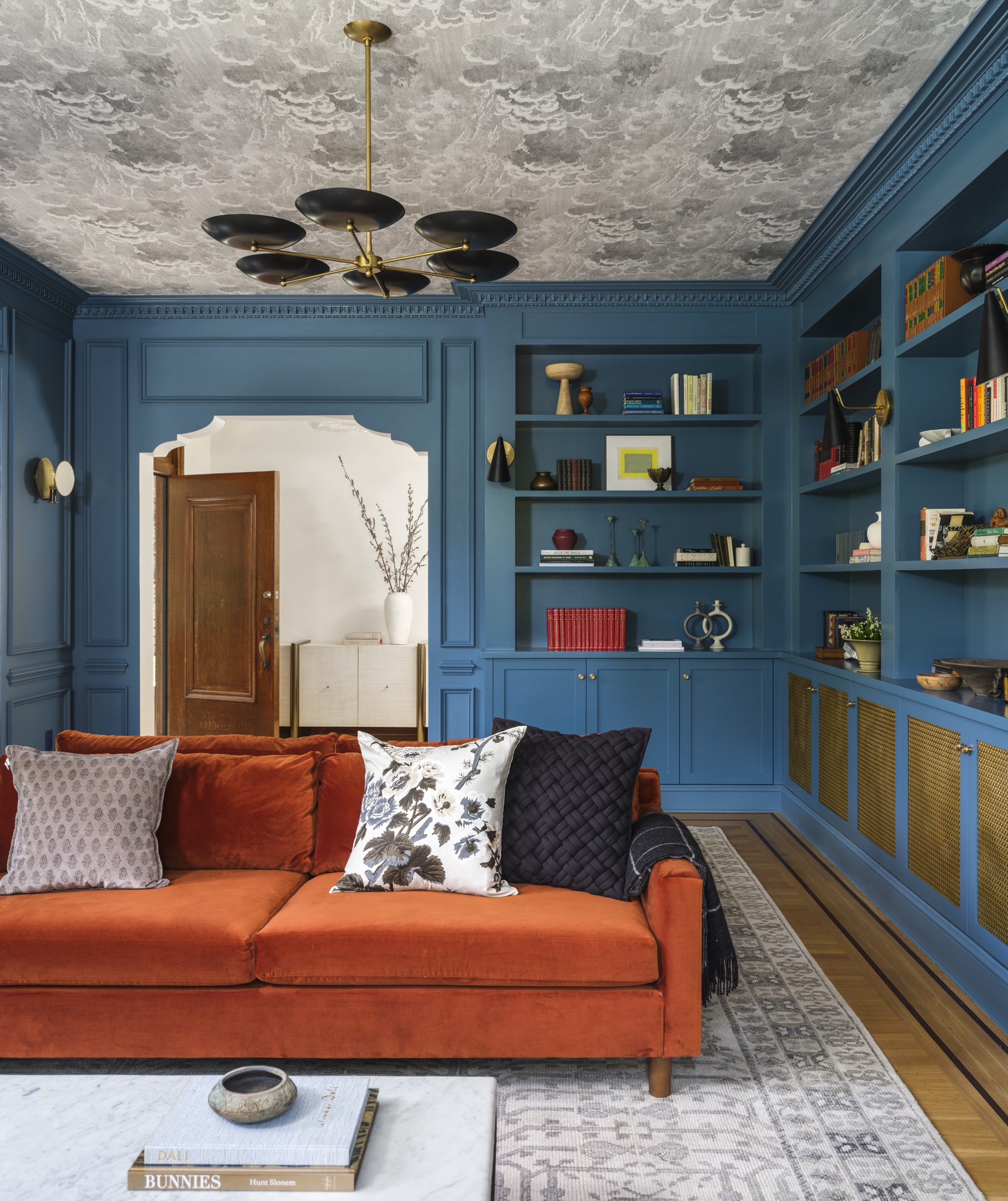 Blå stue med tilpasset fabrikk, tapetert tak og rustsofa av Banner Day Interiors